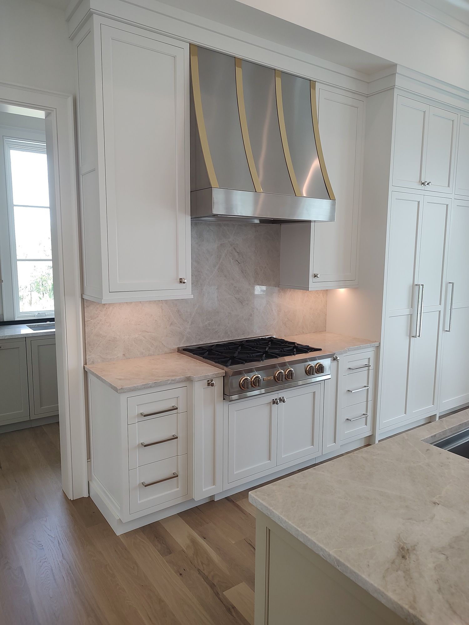 Custom build white cabinets with stainless steel range hood and sandstone counter